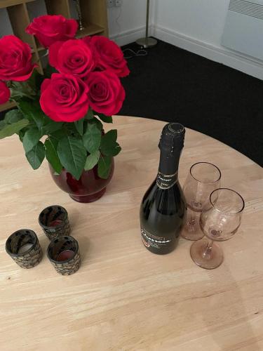2 bedroom apartment in Kidderminster (The place to be) في كيدرمينستر: طاولة مع زجاجة من النبيذ و مزهرية من الورود