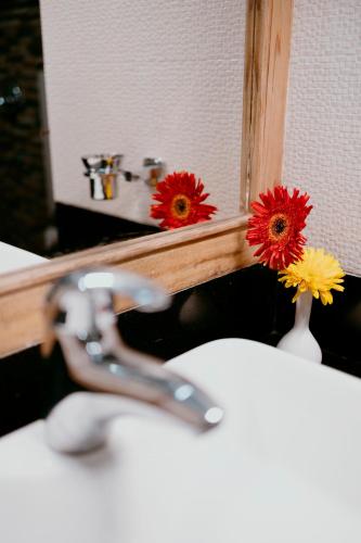 a bathroom sink with a mirror and flowers in a vase at Buddha Retreat in Ravangla