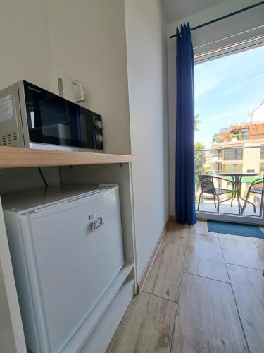 a kitchen with a microwave and a refrigerator and a window at Domek w Parku Hel in Hel