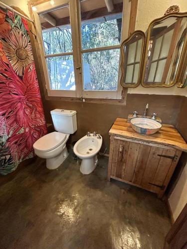 a bathroom with two toilets and a sink and a mirror at Casa corazon in San Marcos Sierras