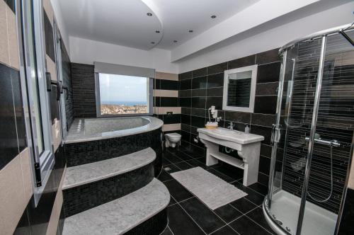 a bathroom with a tub and a sink and a shower at Our Villa Santorini in Akrotiri