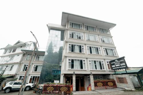 a tall white building with a sign in front of it at Sikkim Tourist Centre in Pelling