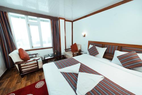 a hotel room with two beds and a chair at Sikkim Tourist Centre in Pelling