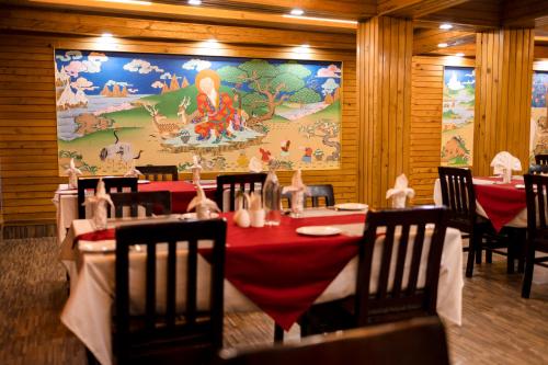 a dining room with a table and chairs and a mural at Sikkim Tourist Centre in Pelling