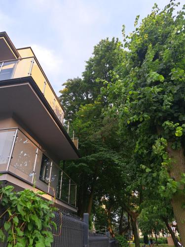 uma casa com uma cerca ao lado de algumas árvores em Domek w Parku Hel em Hel