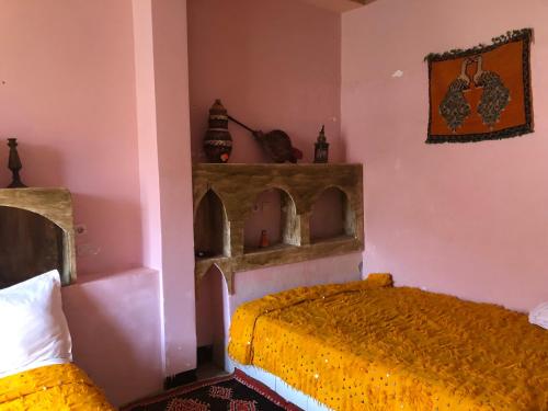a bedroom with a bed with a yellow bedspread at ACHAHOUD CHEz LA BELLE FIBULLE in Aït Fars