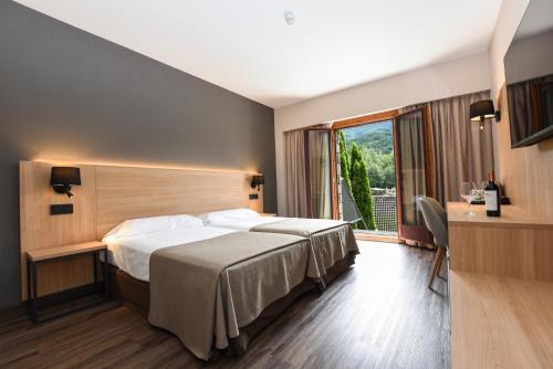 um quarto de hotel com uma cama e uma janela em SOMMOS Hotel Benasque Spa em Benasque