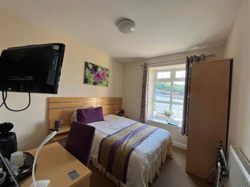 a bedroom with a bed and a desk and a television at Wingfield Hotel 
