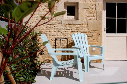 two white chairs sitting next to a building at Au Petit Bonheur de Lorigné in Lorigné