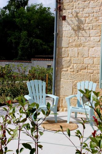 two blue chairs sitting next to a brick wall at Au Petit Bonheur de Lorigné in Lorigné