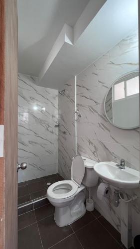La salle de bains est pourvue de toilettes blanches et d'un lavabo. dans l'établissement apartamento familiar villeta, à Villeta