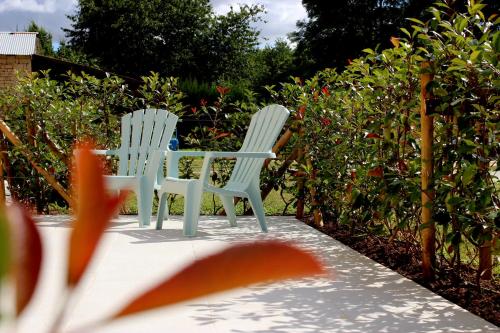 two white chairs sitting on a patio in a garden at Au Petit Bonheur de Lorigné in Lorigné