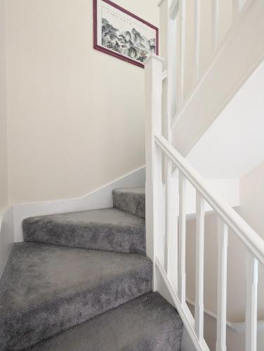 a staircase with white railings and a picture on the wall at Guest Rooms Near City Centre & Dock Free Parking in Liverpool