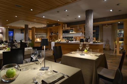 un restaurante con mesas y sillas y copas de vino en MOTA hotel en Livigno