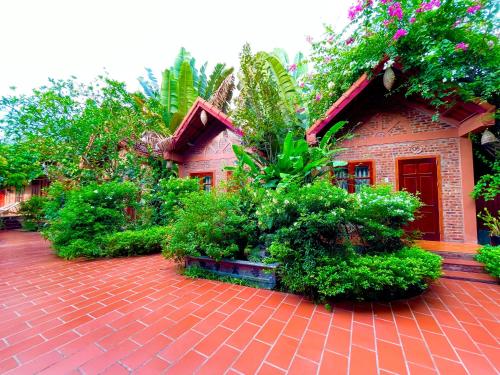 a house with a lot of plants and a brick driveway at Trang An Village Homestay in Ninh Binh