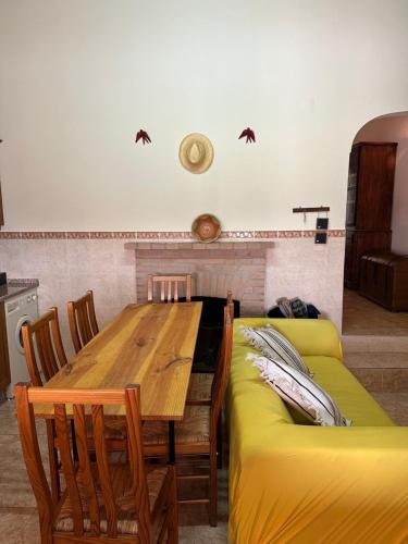 a dining room with a table and a yellow couch at Casa dos AVÓS in Santana de Cambas