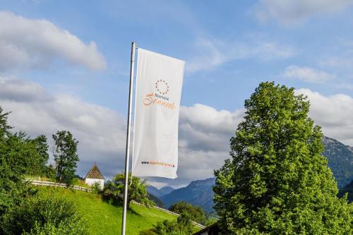 a white flag on a pole in front of some trees at Alpenhotel Sonneck - mit Bergbahnticket in Bad Hindelang
