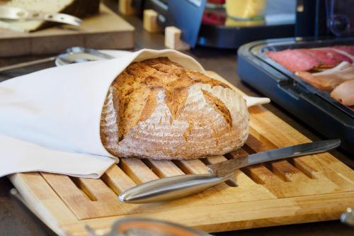 a loaf of bread sitting on a cutting board with a knife at Alpenhotel Sonneck - mit Bergbahnticket in Bad Hindelang