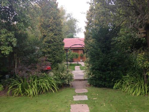 a garden with a pathway leading to a house at Manor Garden Lodge in Wirral