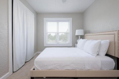 a white bedroom with a white bed and a window at Dragon on Taylor St in Amarillo