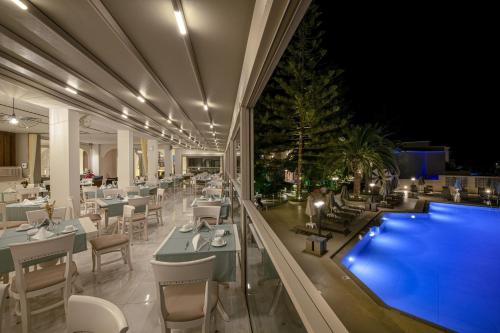 a restaurant with a swimming pool and tables and chairs at Vantaris Luxury Beach Resort in Georgioupolis