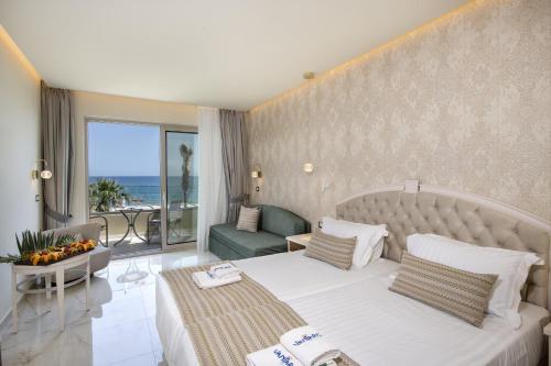 a hotel room with a bed and a balcony at Vantaris Luxury Beach Resort in Georgioupolis