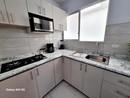 een keuken met witte kasten en een wastafel bij Victoria House-Sun View Hostel in San Isidro