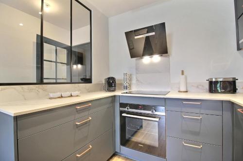 uma cozinha com armários cinzentos, um lavatório e um fogão em L'Universel em Vannes