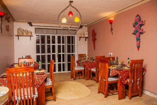 un comedor con mesas y sillas y una lámpara de araña en JET VILLAS ENTEBBE ( JVE ) en Entebbe