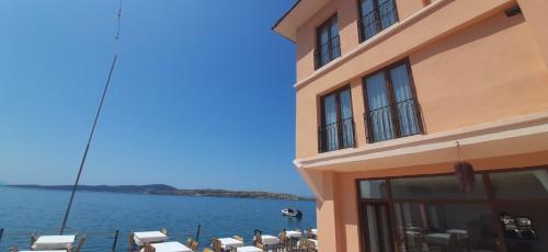 a building with tables and chairs next to the water at CasaLyma Ayvalık in Ayvalık