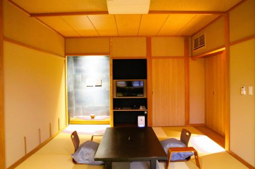a dining room with a black table and chairs at Ichidaya in Toyooka