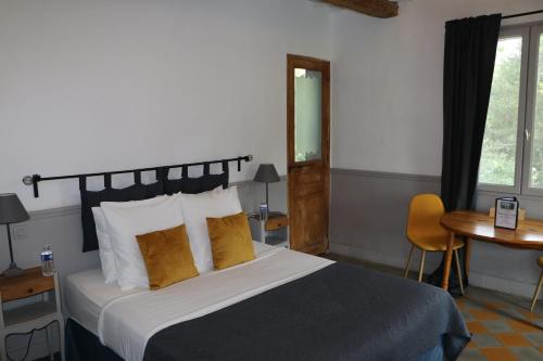 a bedroom with a bed and a table and a window at Le Mas des Cerisiers JACUZZI et SAUNA inclus pour tous les logements in Avignon