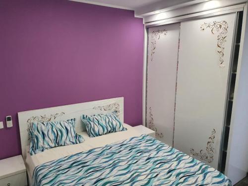 um quarto com paredes roxas e uma cama com almofadas em جنان الحمامات اقامة em Hammamet