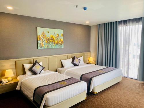 a hotel room with two beds and a painting on the wall at Hera Luxury Hotel in Ho Chi Minh City