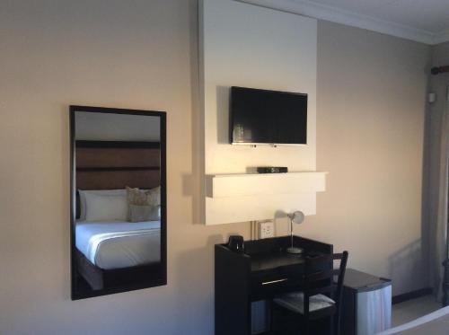a bedroom with a mirror and a bed and a tv at SteyMorr Guesthouse in Maun
