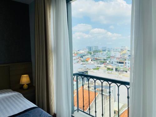 a bedroom with a view of a city from a window at Hera Luxury Hotel in Ho Chi Minh City