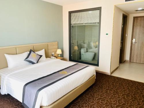 a bedroom with a large white bed and a bathroom at Hera Luxury Hotel in Ho Chi Minh City