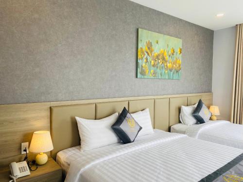 a hotel room with two beds and a painting on the wall at Hera Luxury Hotel in Ho Chi Minh City