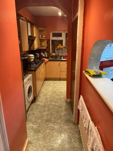 a kitchen with orange walls and a washer and dryer at Walpole House in London