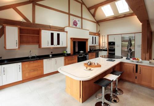 a large kitchen with wooden cabinets and a large island at Whytings Stud Barn 2 in Horsham