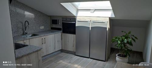 a kitchen with a stainless steel refrigerator and a skylight at Hotel Brisa del Mar in O Grove
