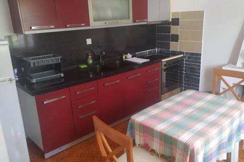 een keuken met rode kasten, een wastafel en een tafel bij Λευκό σπίτι in Ksamil
