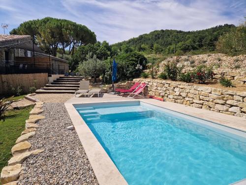 una piscina en un patio con una pared de piedra en Gite de charme La Martinelle, en La Bégude-de-Mazenc