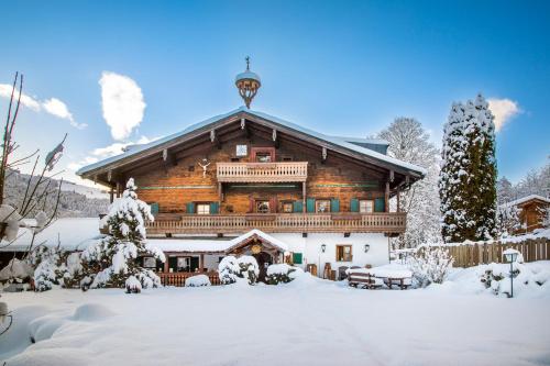 Cabaña de madera grande con nieve en el suelo en Ferienhof Millinghof, en Leogang