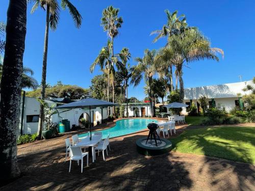 a resort with a swimming pool and palm trees at Villa Grande Lodge in Louis Trichardt