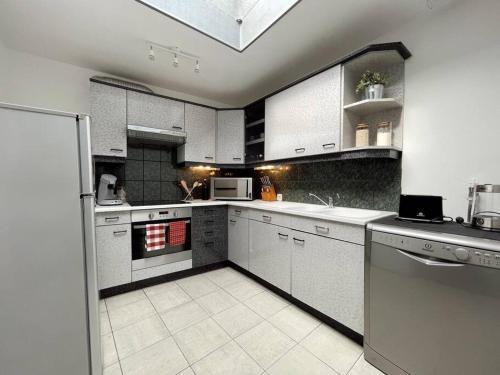 uma grande cozinha com armários e electrodomésticos brancos em Maison Opaline em Berck