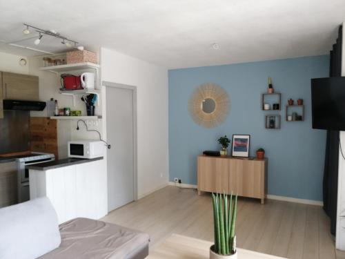 Il comprend un salon avec des murs bleus et une cuisine. dans l'établissement Appartement au pied des dunes, à Seignosse
