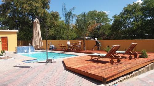 - une piscine avec une terrasse, des chaises et un parasol dans l'établissement SteyMorr Guesthouse, à Maun