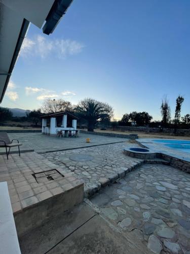 eine Steinterrasse mit einem Pool und einem Haus in der Unterkunft Hotel Poneloya in Tarija