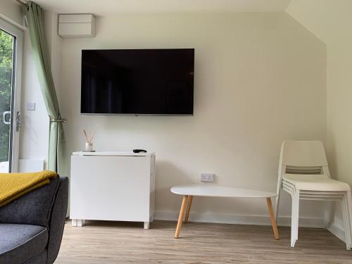 a living room with a flat screen tv on the wall at Beach Woods Coastal Path chalet in Pembrokeshire